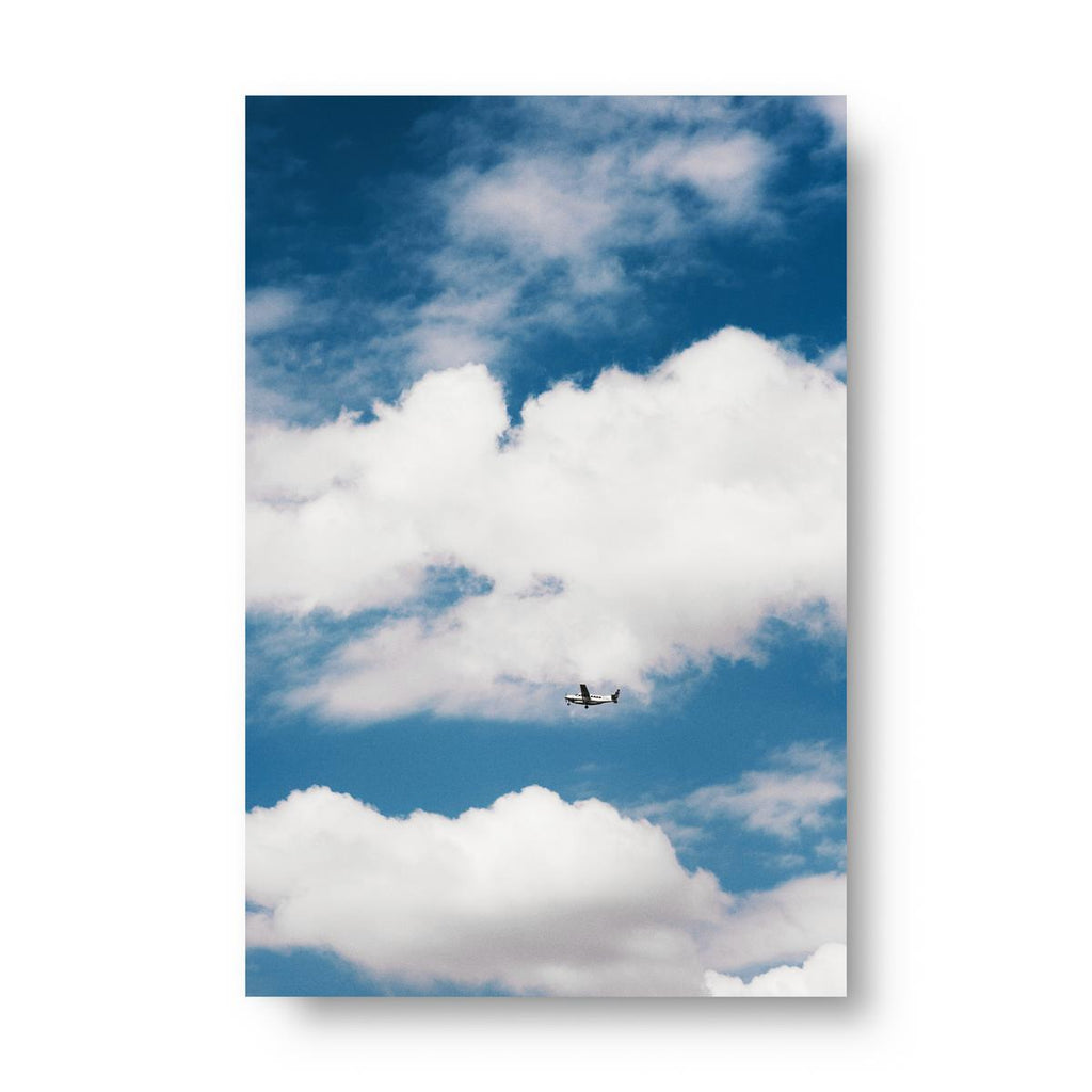 Airplane flying through a blue sky with white clouds. Poster.