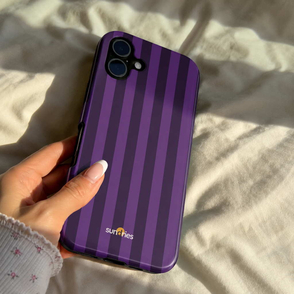 Hand holding a purple striped phone case with 'sunries' branding on a light fabric background