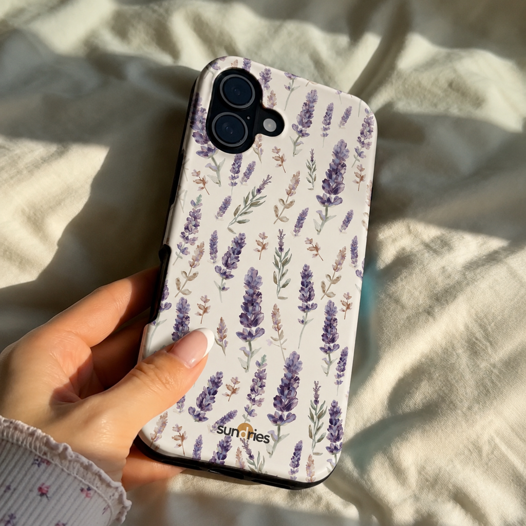 Hand holding a phone case with lavender design on a light fabric background