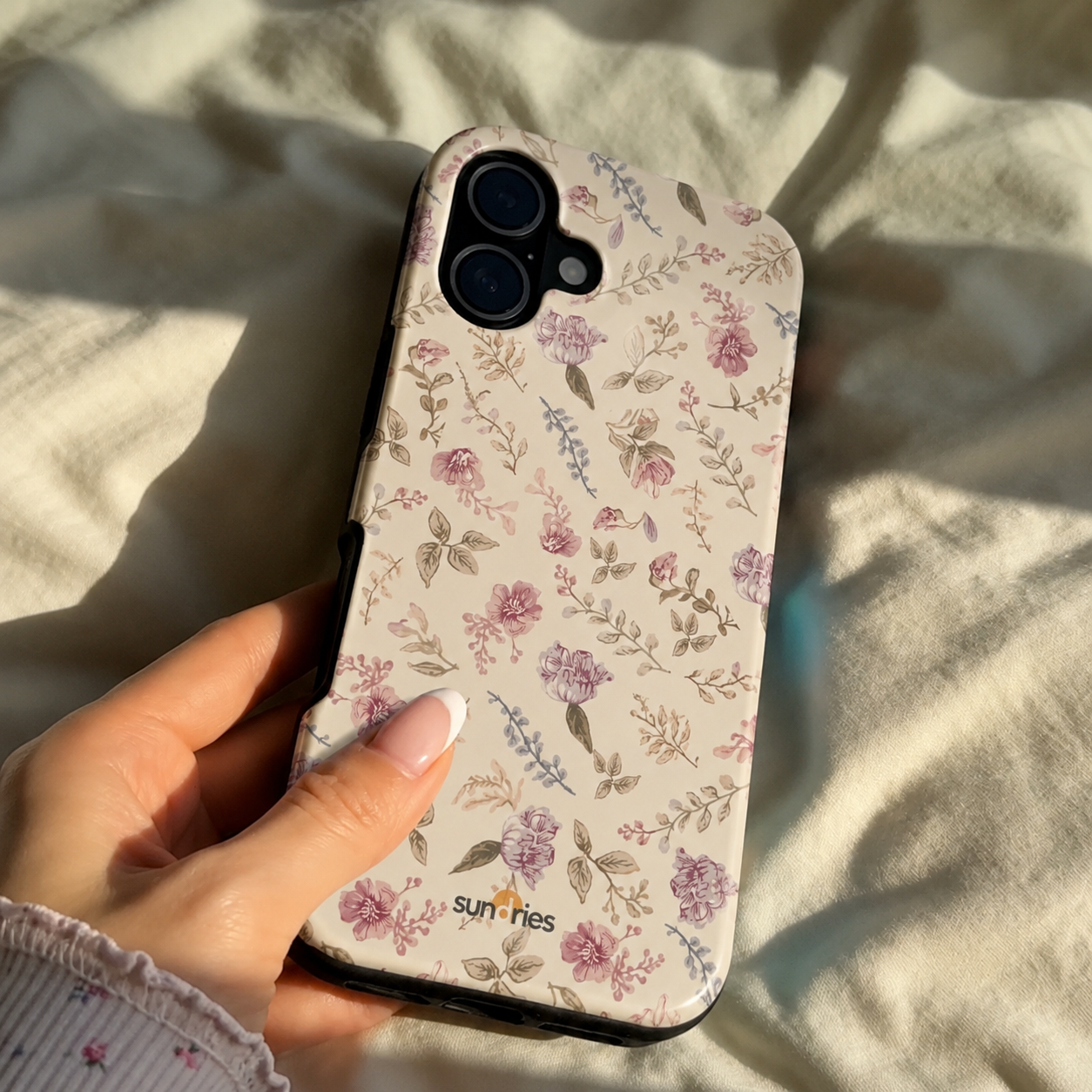 Floral phone case held by a hand on a light fabric background