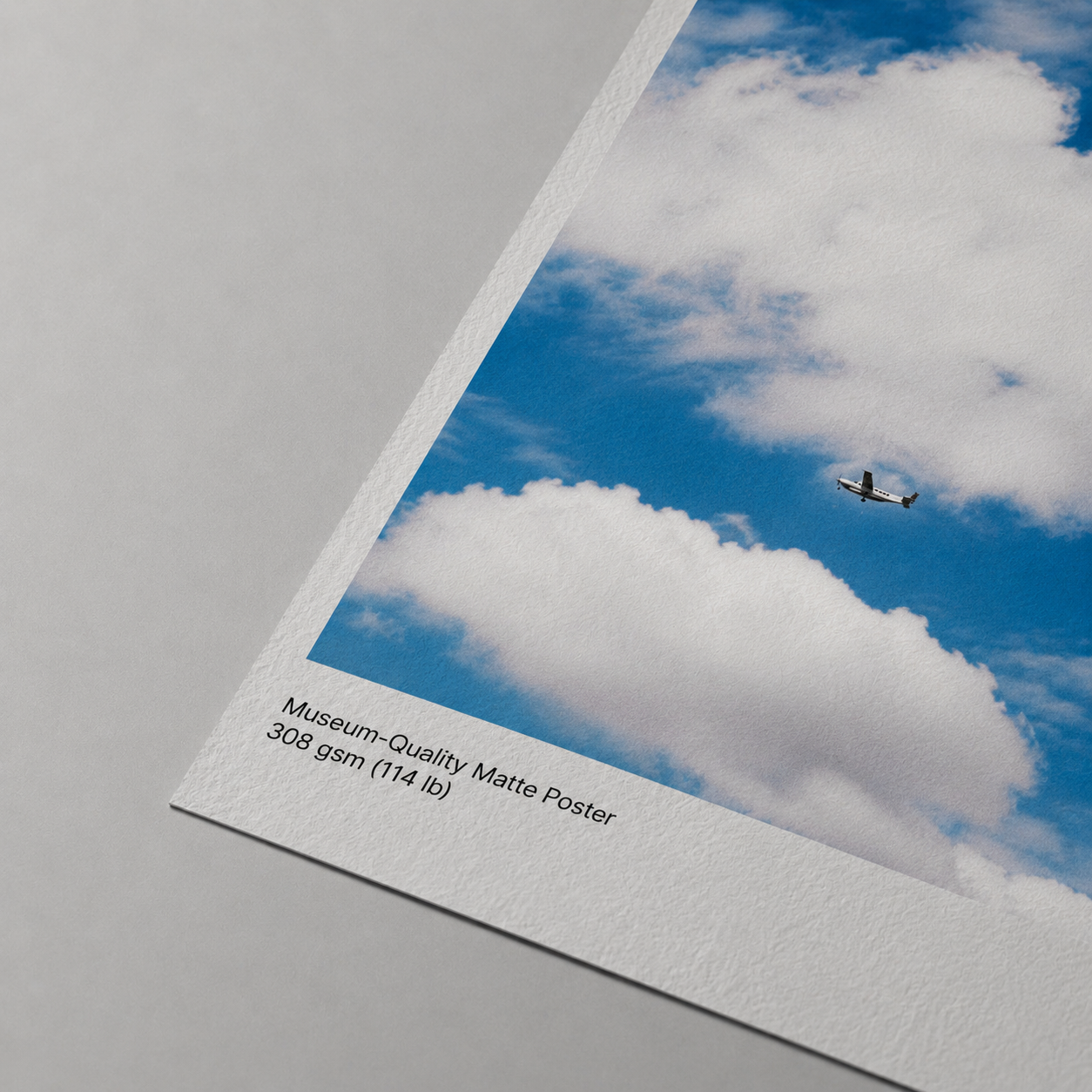Museum-quality matte poster with an airplane flying through a blue sky with clouds.