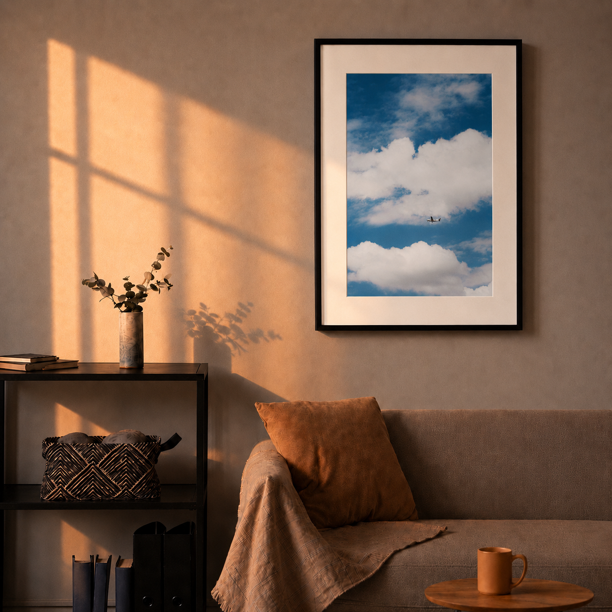 Framed poster of a blue sky with clouds on a wall above a sofa.