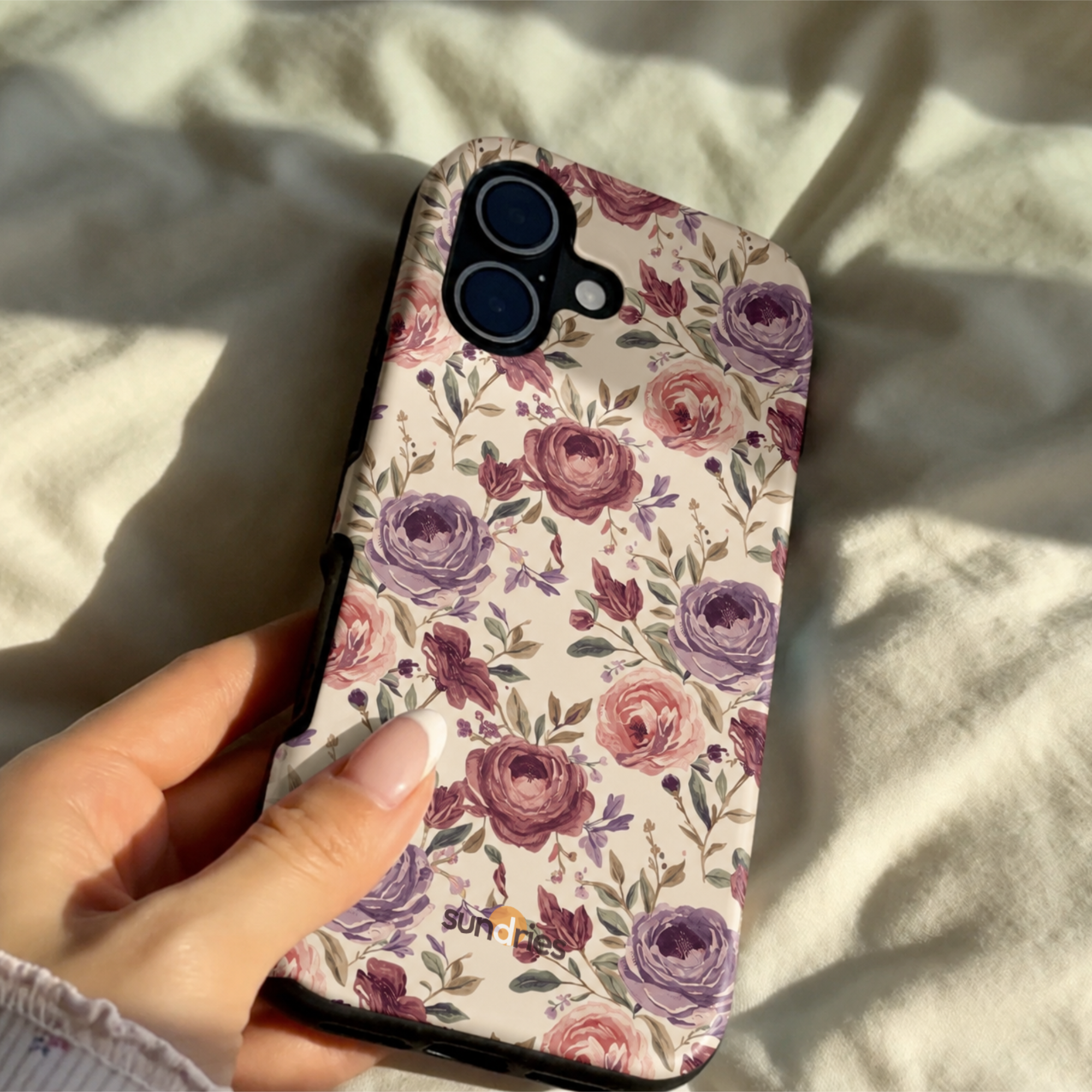 Floral phone case held by a hand on a light fabric background